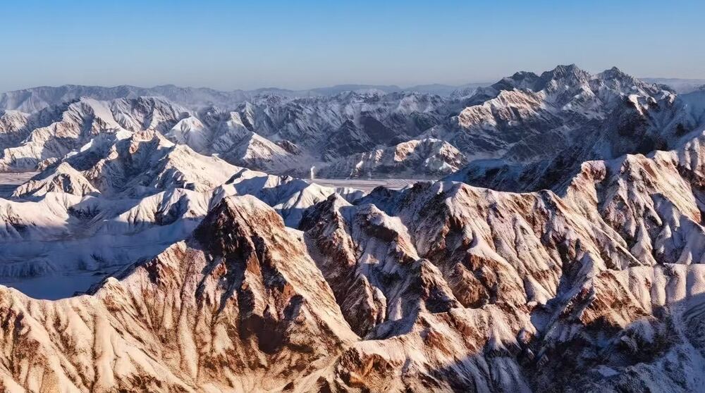 Rugged snow-dusted peaks of the Kunlun mountain range at golden hour